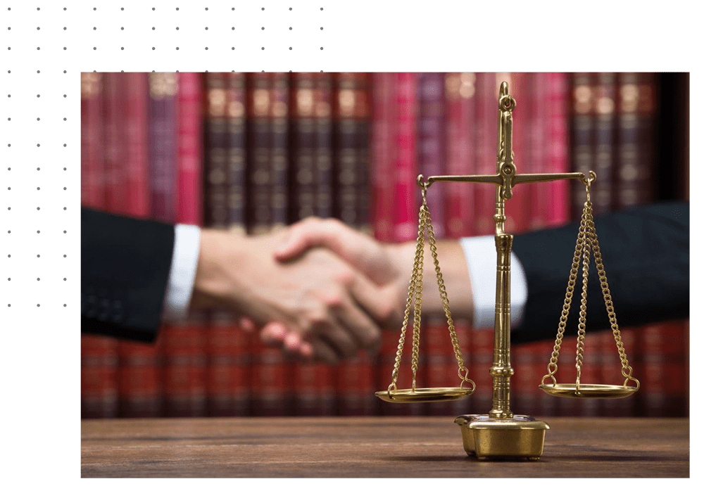A law firm with two people shaking hands in front of the scales.