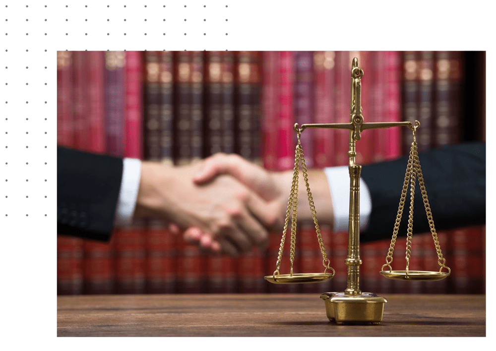 A law firm with two people shaking hands in front of the scales.